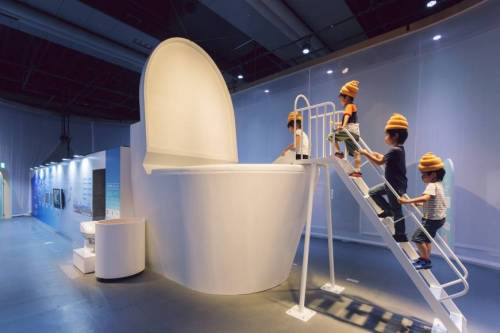 Children climbing into giant toilet